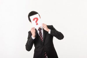 ?で顔を隠すスーツ男性